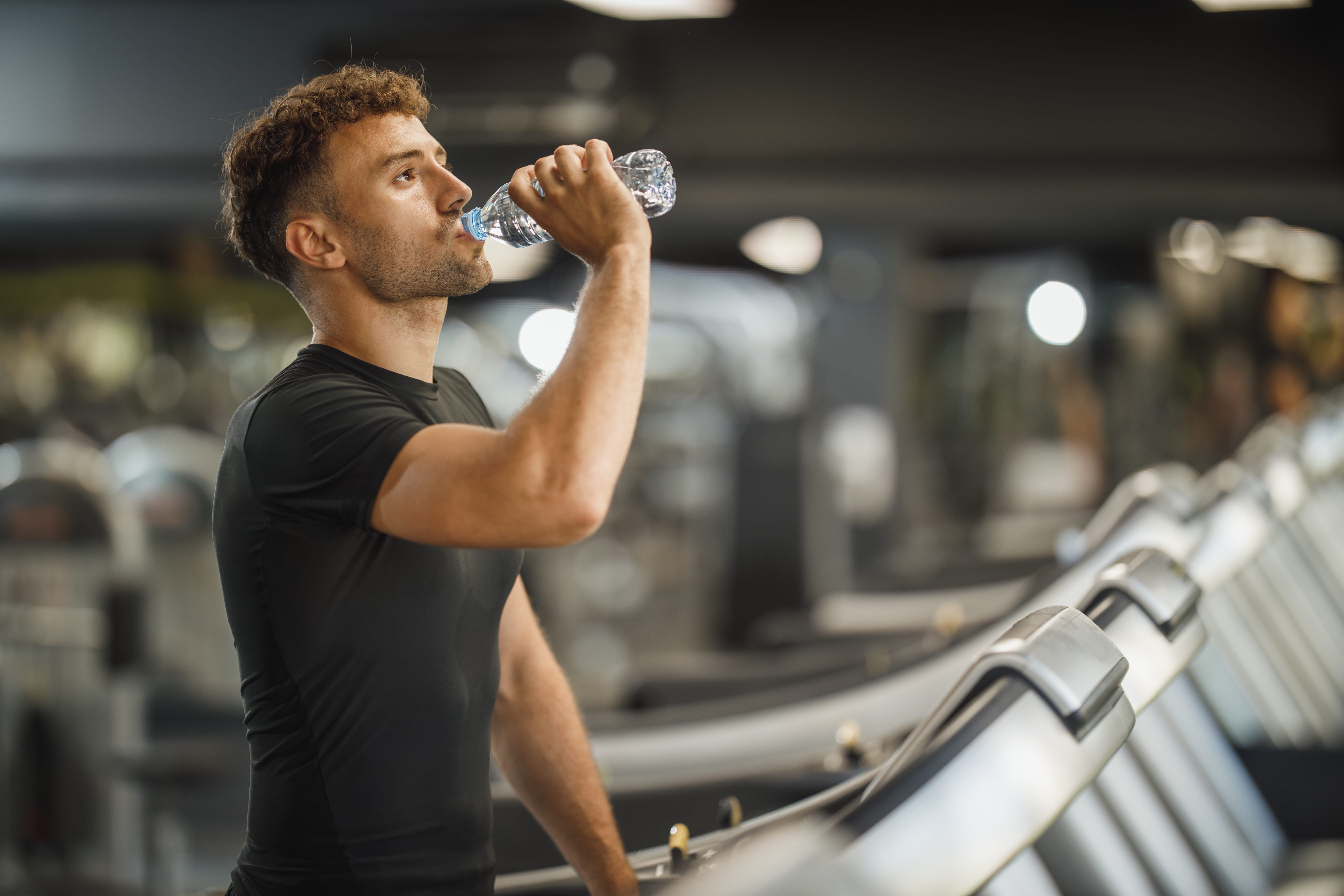 Image of man drinking water while on treadmill